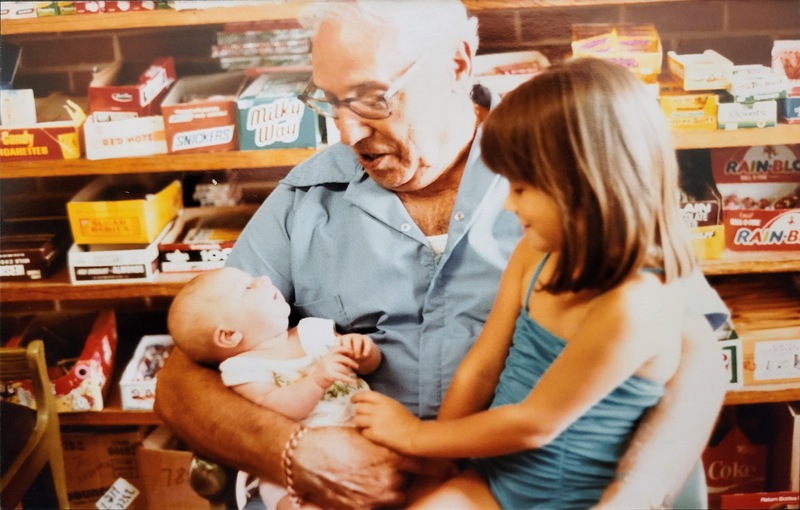 Raymond holding his grandkids in his West Main grocery store.