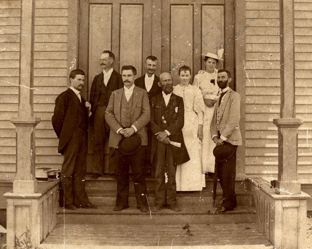John McNeese (holding white paper) and others standing on the steps of the Lake Charles School.